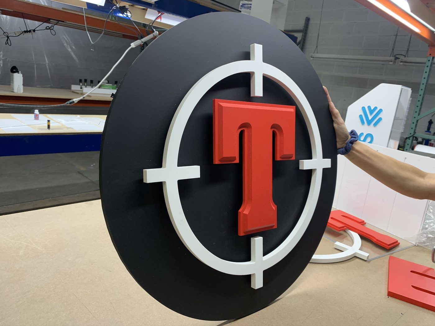 Dimensional layered logo sign being held in the shop