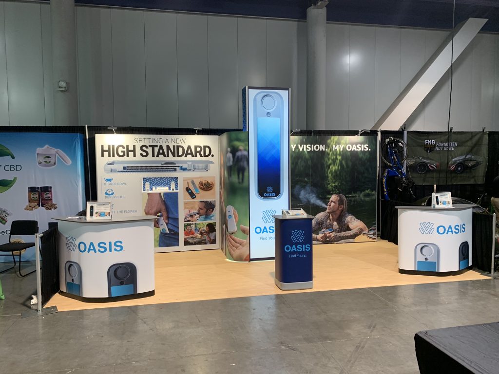 Oasis trade show booth with backlit tower and branded counters